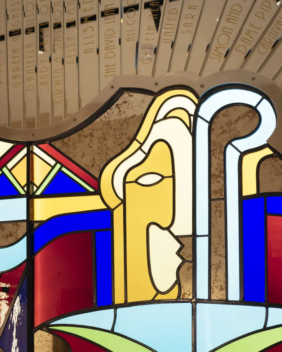 A colourful glass wall panel with the outline of a face in it's design.