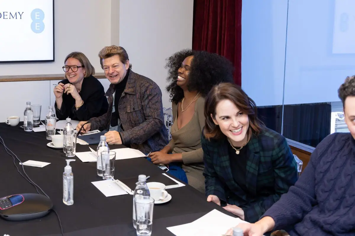 Four people sat down the right hand side of a black table smiling at the camera.