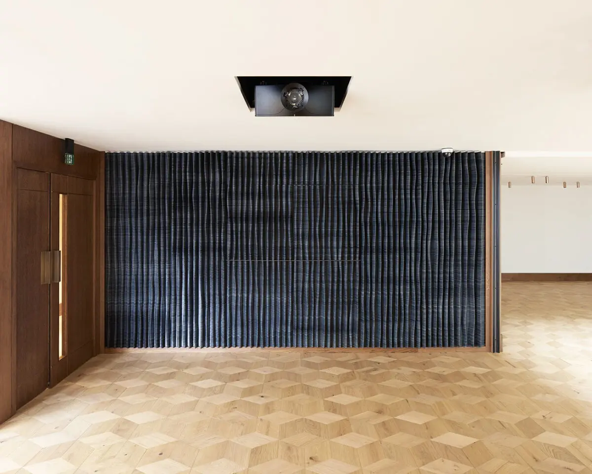 A room with a white ceiling and projector camera, and a dark dividing wall in the centre.