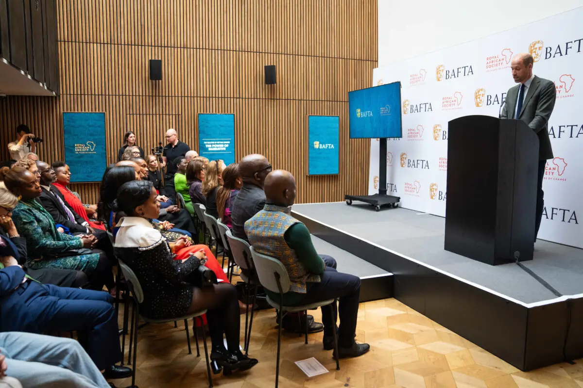 An audience facing a stage where His Royal Highness, The Prince of Wales, is stood giving a presentation.