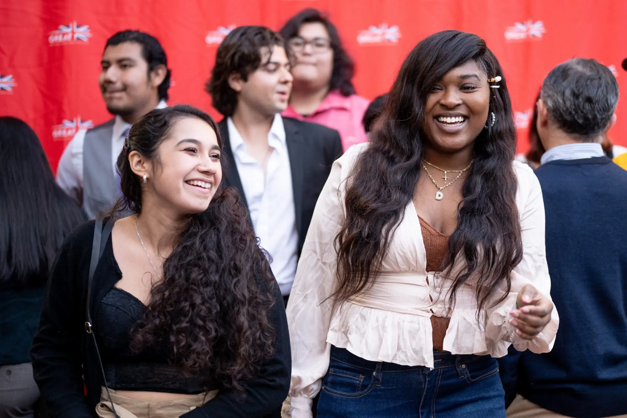 Two smiling young women both with long dark wavy hair.