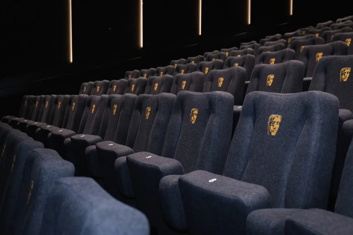 A close up photo of large blue cinema seats with the BAFTA logo on them.