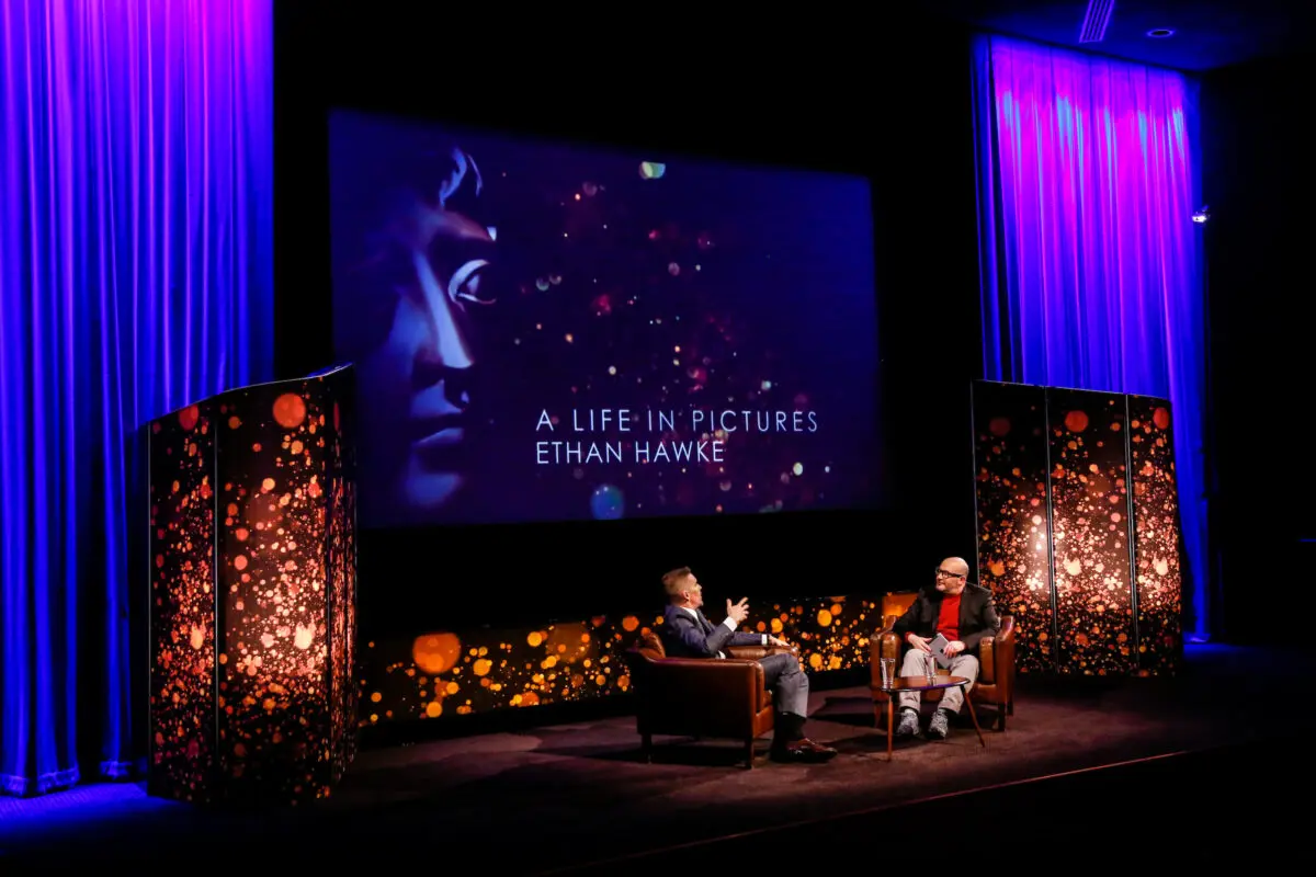 Two men sat in armchairs on a stage with a screen which reads 'A Life in Pictures: Ethan Hawke' behind them.