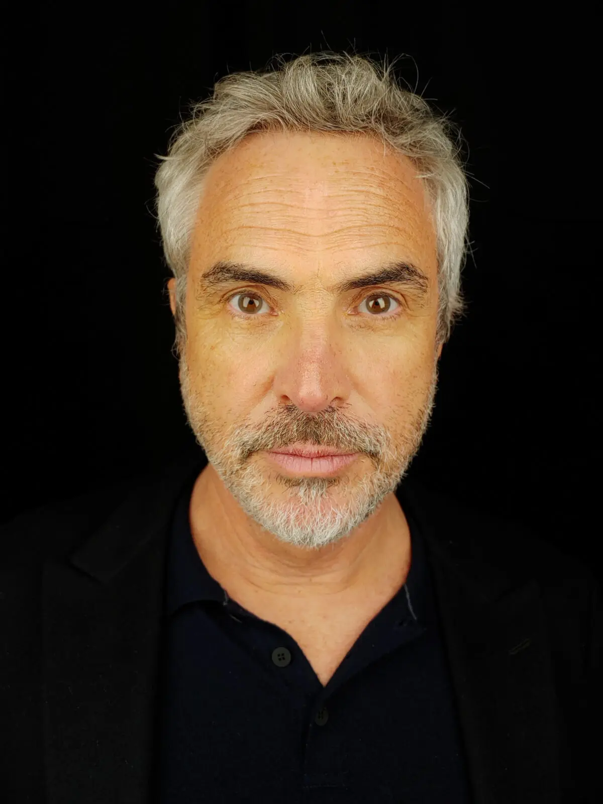 Director Alfonso Cuaron. A man with grey hair and a greying beard wearing a black polo neck.