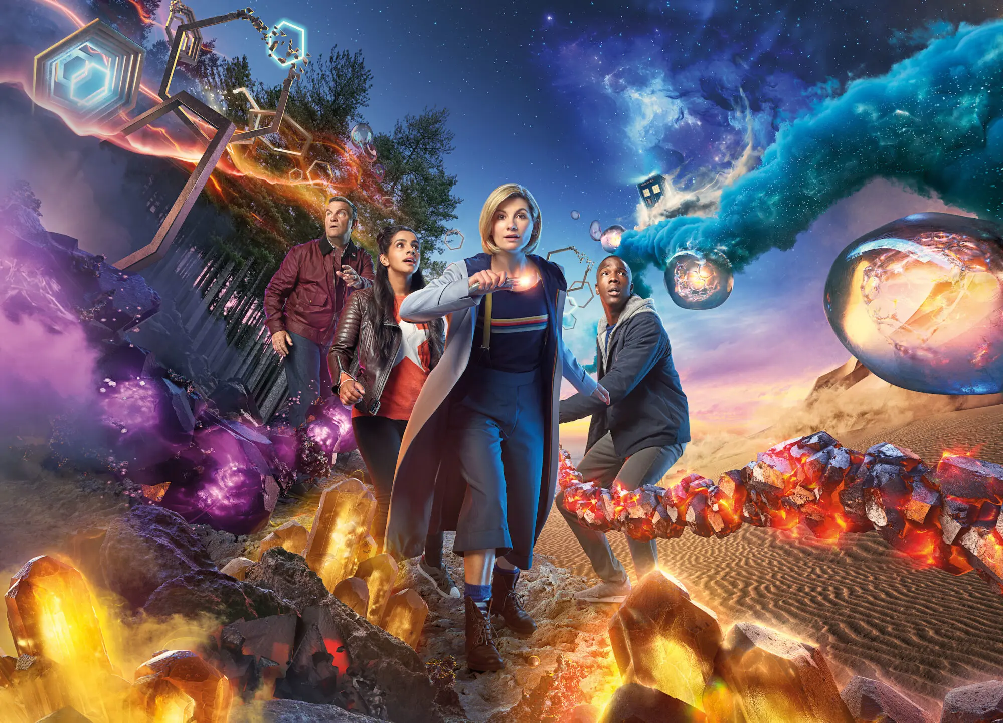 Four people in what looks like a space scene. There is a blonde woman with a bob at the front leading the way wearing a long coat and holding a torch.