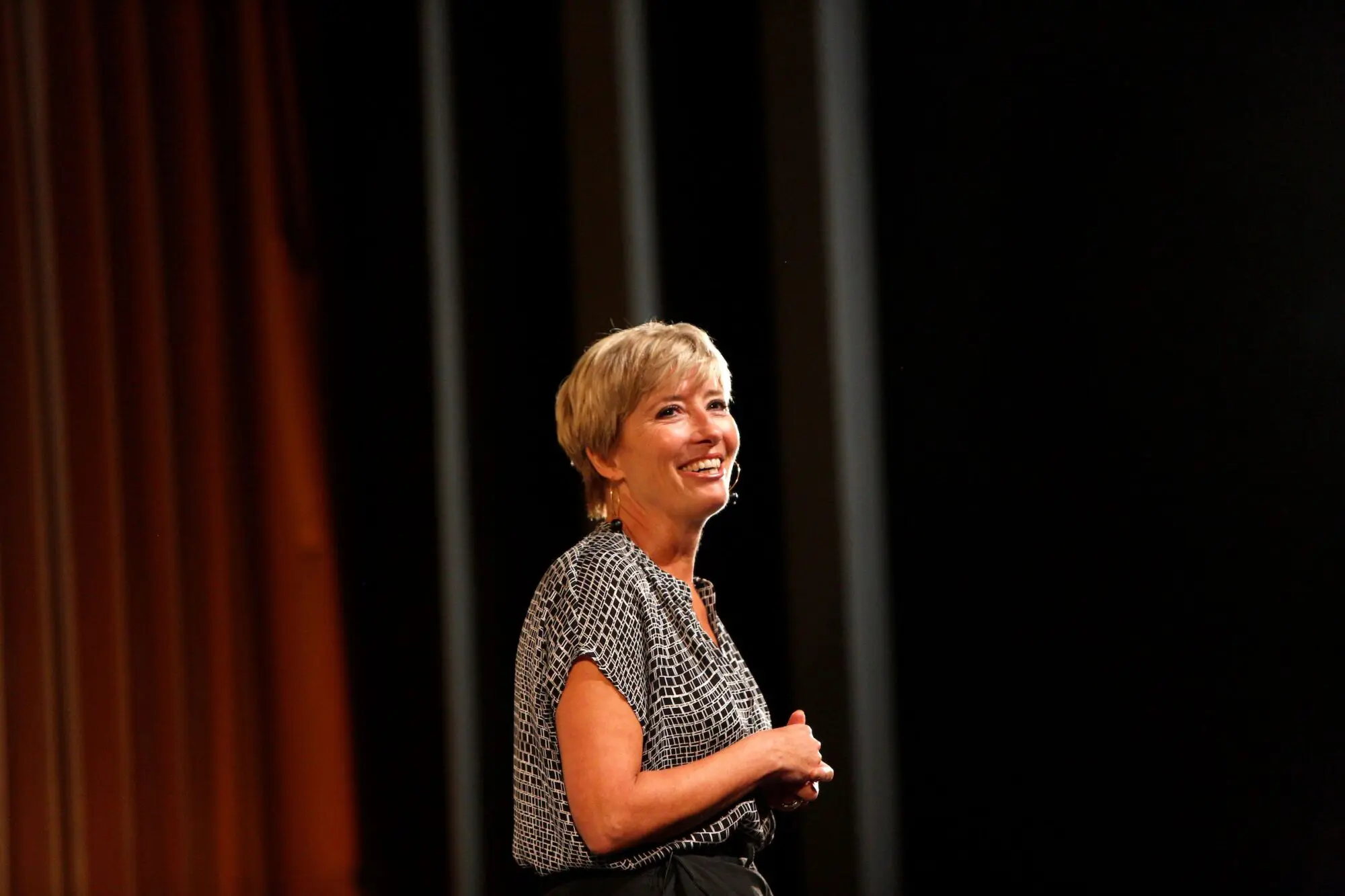 Emma Thompson. A white woman with a blonde pixie crop stood on stage wearing a black and white top.
