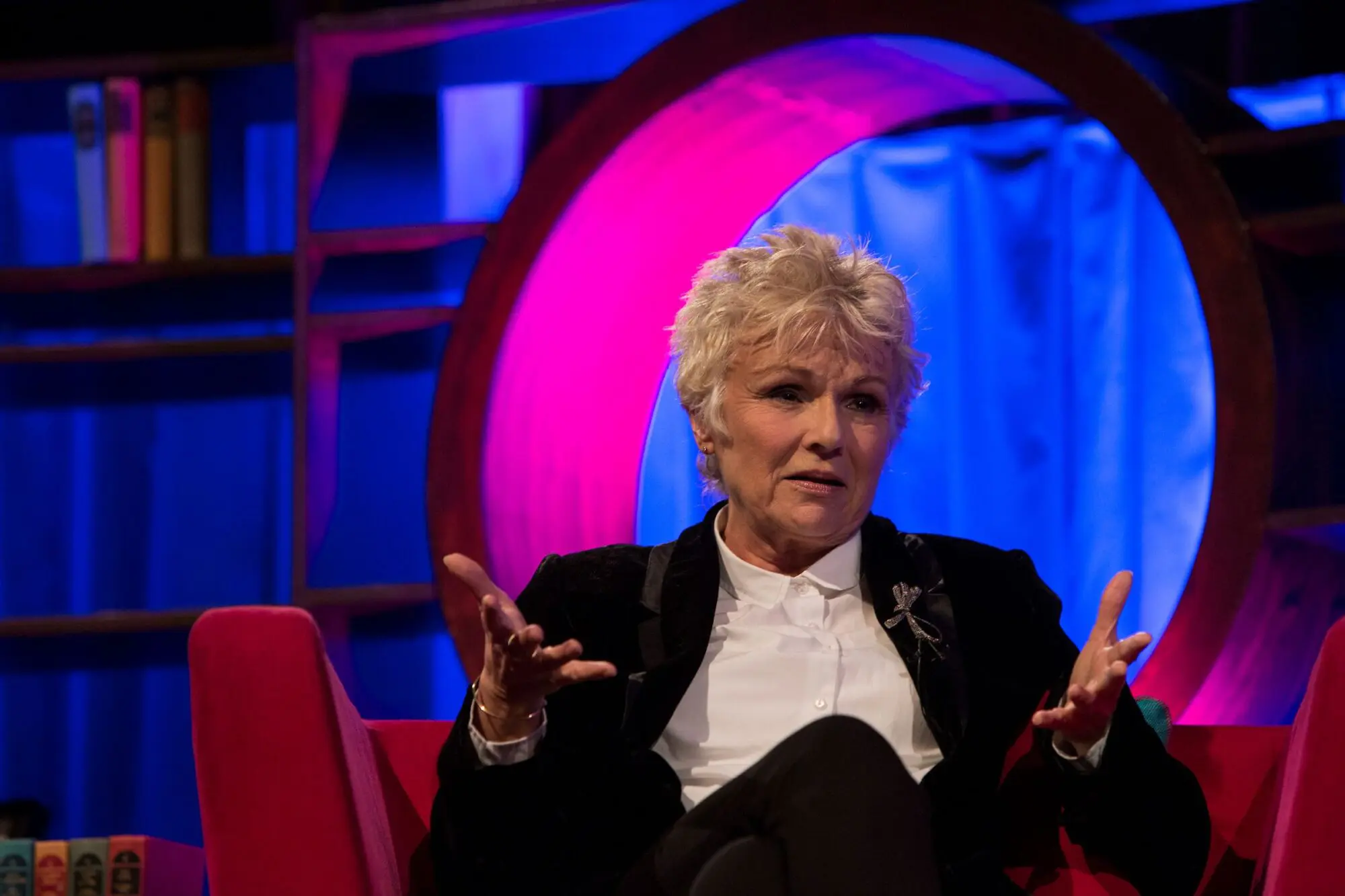 Julie Walters. A woman with short white hair wearing a white shirt and black suit.