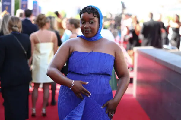 Lolly Adefope, a black woman wearing a royal blue strapless gown and matching headscarf on the red carpet.