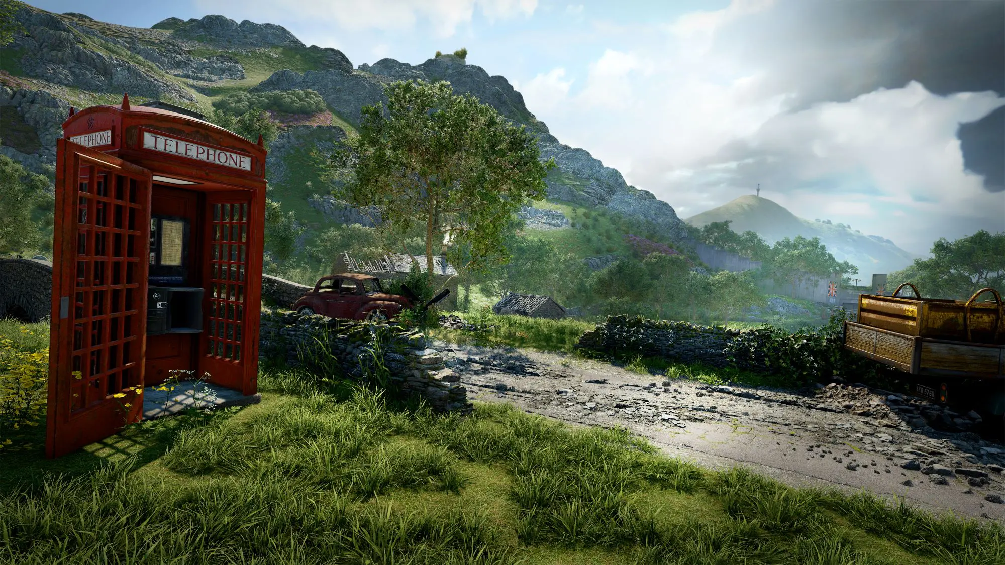 A still from the game Atomfall. A small country road with a deserted telephone box, crashed car and knocked down wall visible.