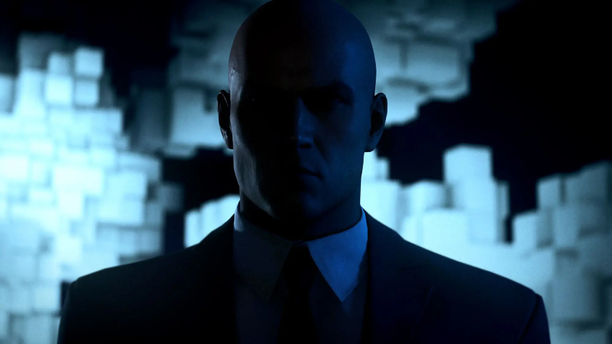 A still from the video Hitman World of Assassination. A shadowy figure with a bald head, standing in the dark wearing a dark suit and tie.